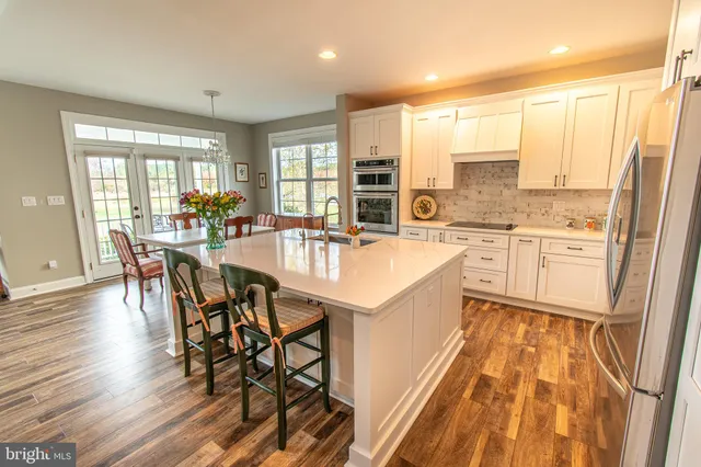 a large white kitchen with a large window and stainless steel appliances