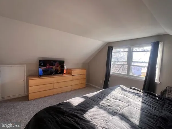 a bedroom with a bed and a flat tv screen on a dresser