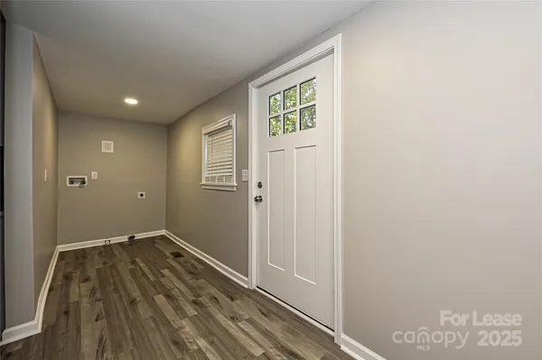 a view of a hallway with wooden floor and a bathroom