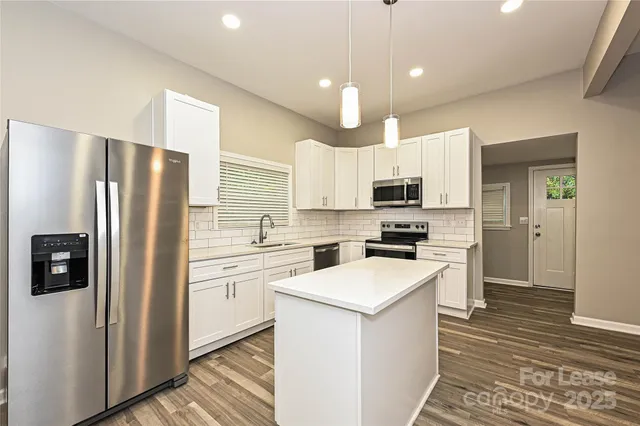 a kitchen with a refrigerator a stove top oven a sink and cabinets