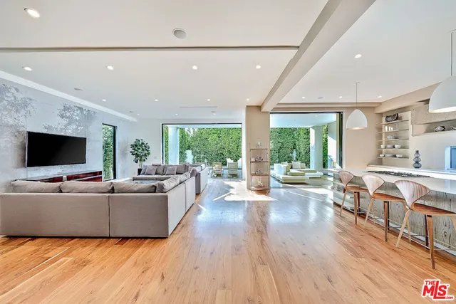 a living room with furniture kitchen view and a large window