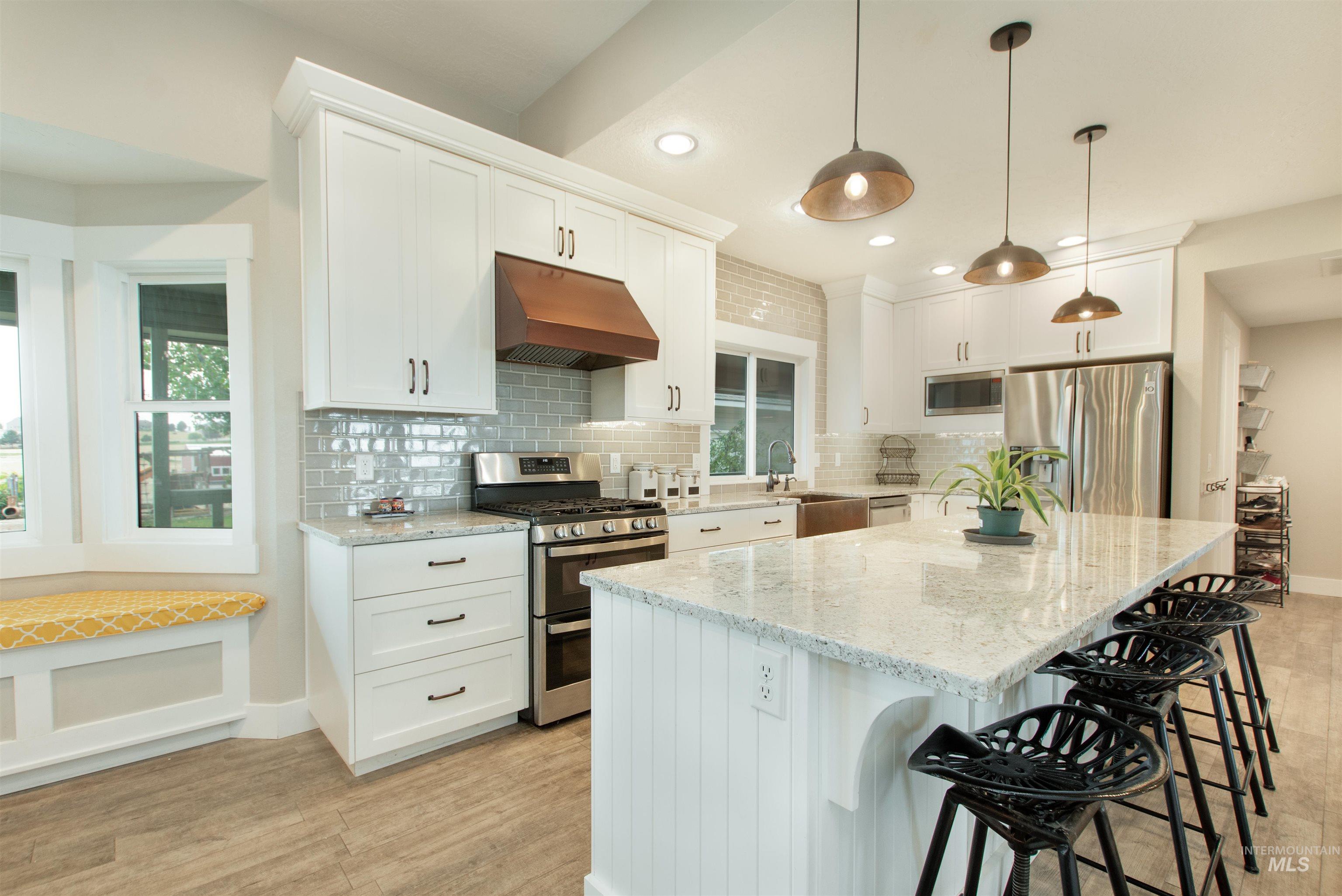 12369 Deer Flat Road Nampa, ID 83686 - Photo 13 of 50 Spacious room featuring wood-finish flooring, a brick fireplace with a wood-burning insert, and white trim windows