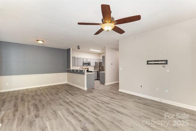 a view of kitchen and empty room with wooden floor