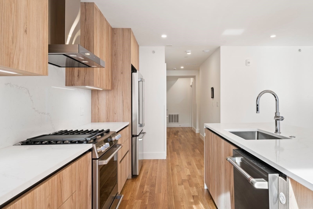 6 Devine Way, Unit 2 Boston, MA 02127 - Photo 12 of 39 a kitchen with stainless steel appliances granite countertop a sink stove and refrigerator