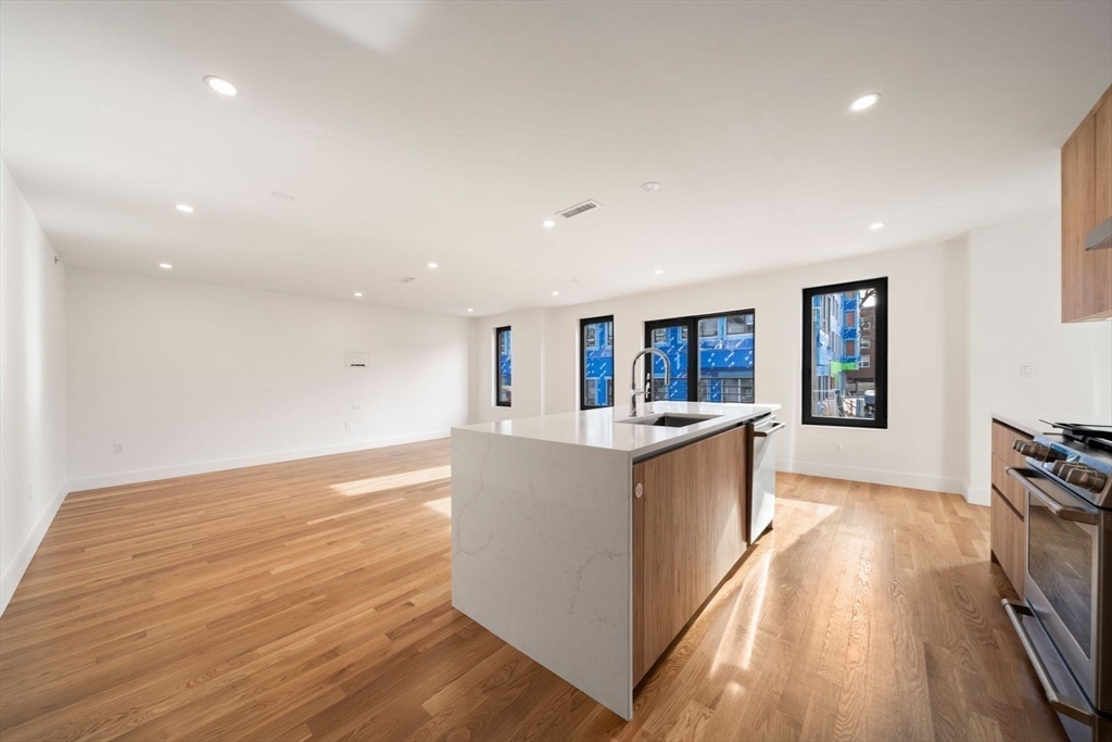 6 Devine Way, Unit 2 Boston, MA 02127 - Photo 13 of 39 a large kitchen with kitchen island wooden floors and stainless steel appliances