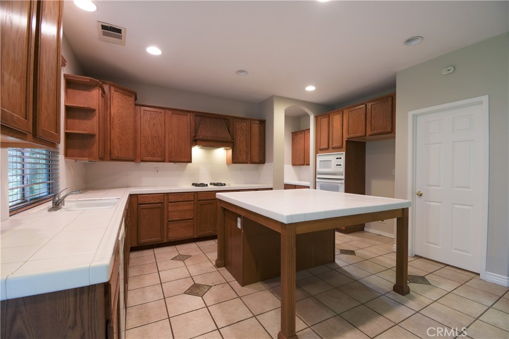 39705 Primrose Circle Murrieta, CA 92563 - Photo 7 of 31 a kitchen with a sink a stove a refrigerator cabinets and a dining table