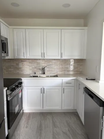 a kitchen with granite countertop white cabinets and stainless steel appliances