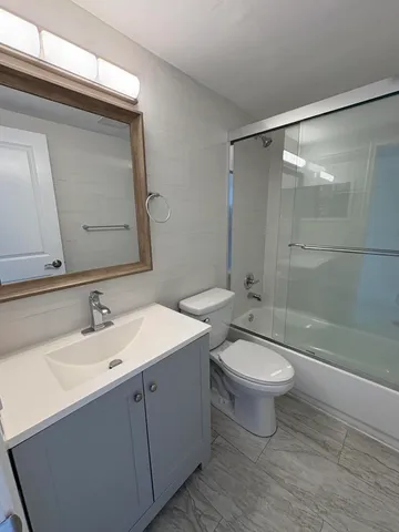 a bathroom with a double vanity sink toilet mirror and shower