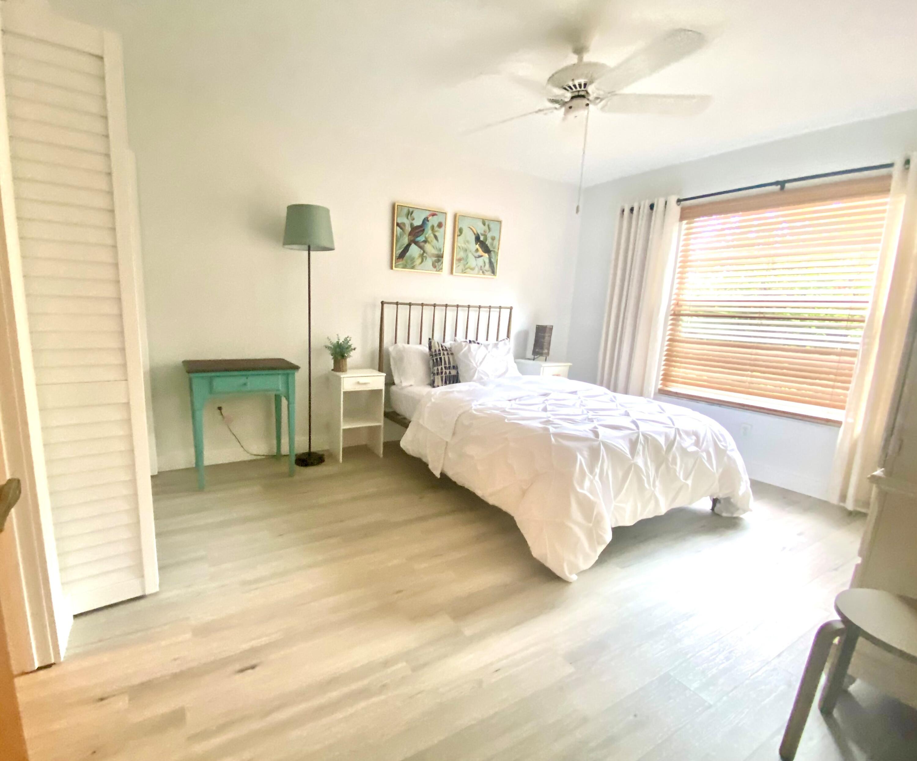 8356 Southeast Croft Circle, Unit O3 Hobe Sound, FL 33455 - Photo 11 of 23 a bedroom with a bed next to a window with a chandelier