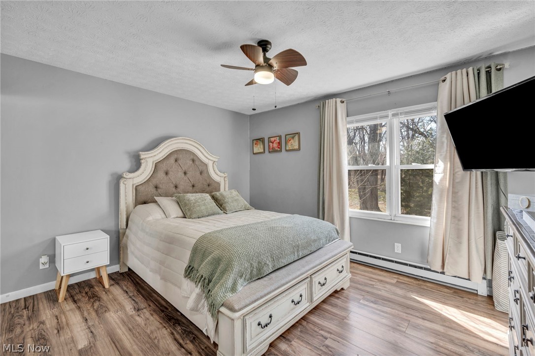54 Park Road Painesville, OH 44077 - Photo 13 of 38 Bedroom with baseboard heating, wood finished floors, ceiling fan, and a textured ceiling