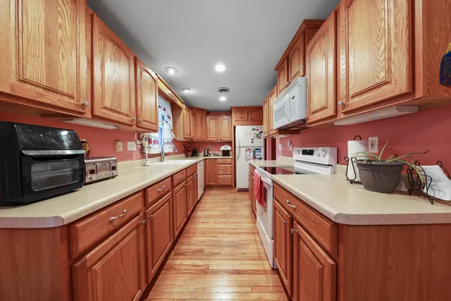 a kitchen with stainless steel appliances granite countertop a sink a stove and a wooden cabinets