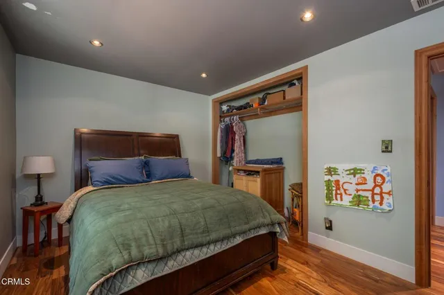 a bedroom with a bed and a flat tv screen on the dresser
