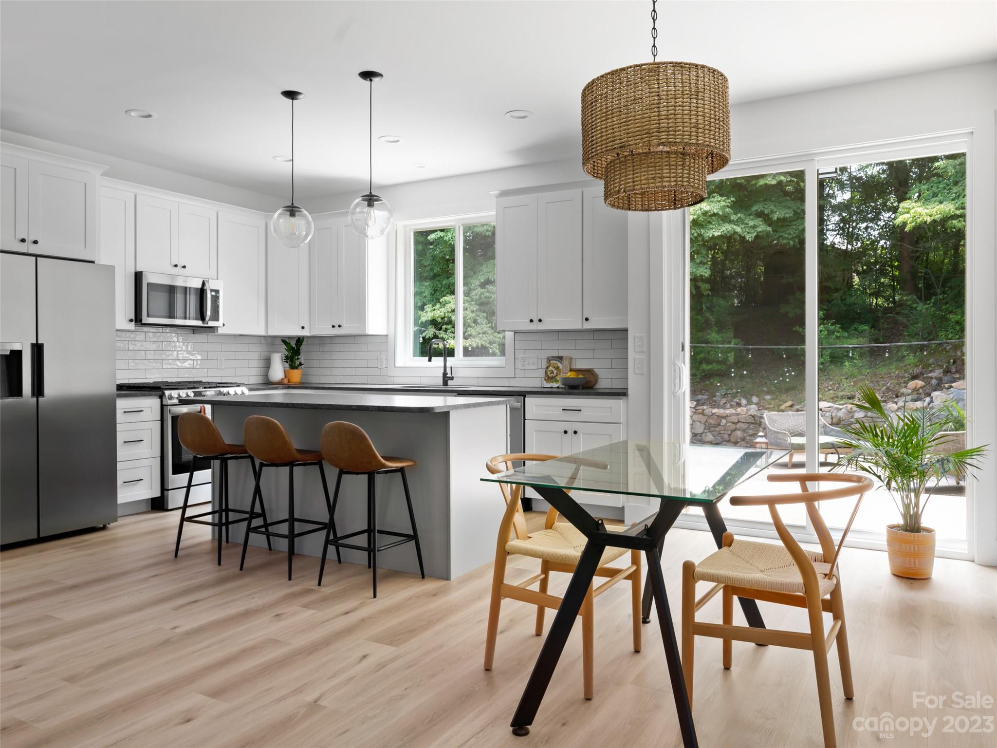 67 Raleigh Road Asheville, NC 28803 - Photo 13 of 43 a kitchen with stainless steel appliances granite countertop a stove a refrigerator a microwave a dining table and chairs with wooden floor