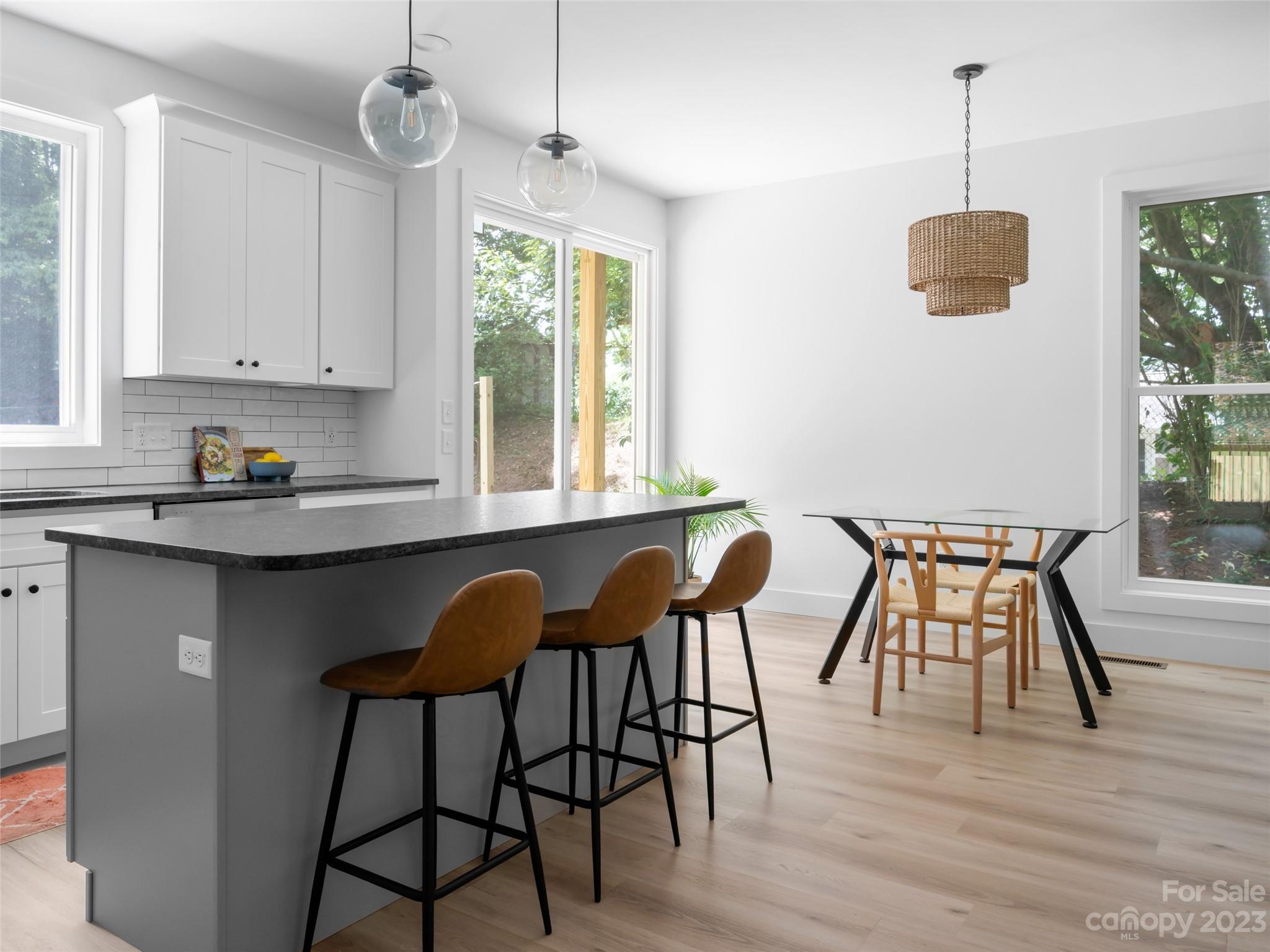 67 Raleigh Road Asheville, NC 28803 - Photo 15 of 43 a kitchen with stainless steel appliances granite countertop white cabinets a dining table and chairs with wooden floor