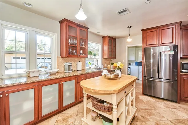 a kitchen with stainless steel appliances granite countertop a refrigerator a stove and a sink with cabinets