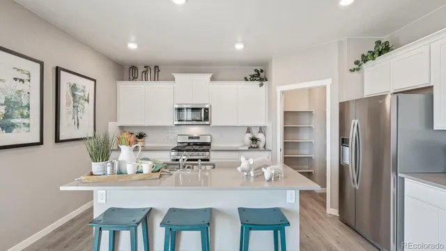 a kitchen with stainless steel appliances granite countertop a dining table chairs refrigerator and cabinets