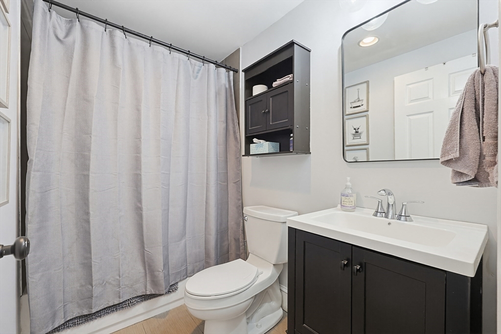 48 Calumet Street, Unit 2 Revere, MA 02151 - Photo 11 of 30 a bathroom with a sink a toilet a mirror and shower curtain