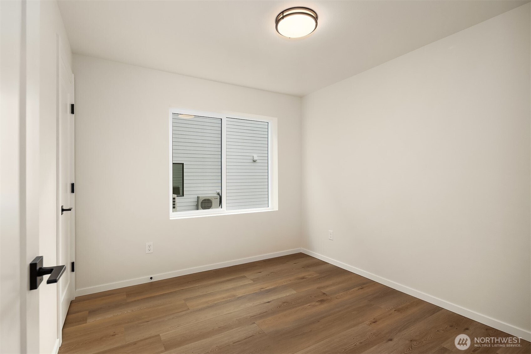 6503 Dibble Avenue Northwest Seattle, WA 98117 - Photo 11 of 15 an empty room with wooden floor and windows