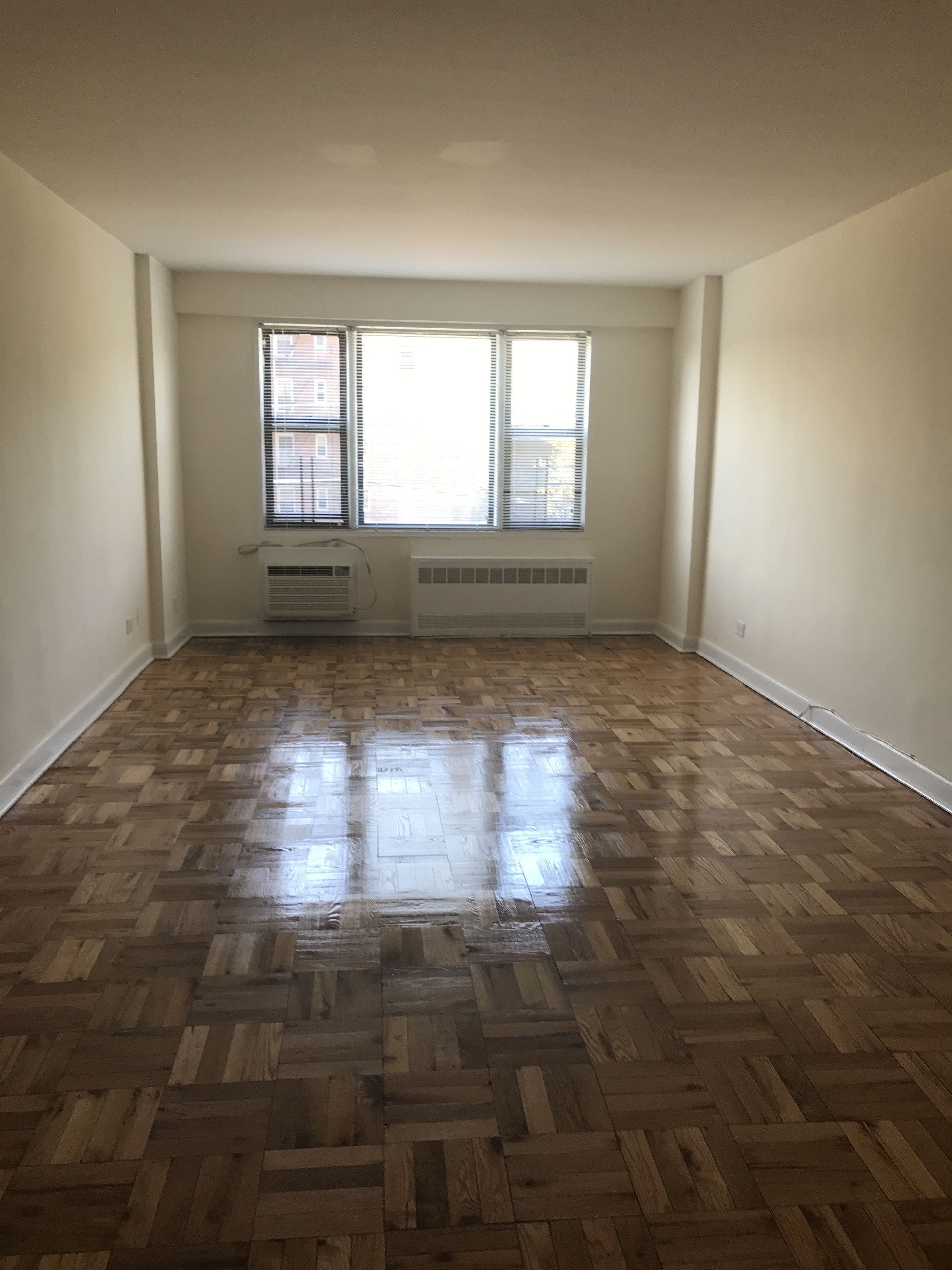 59-17 Junction Boulevard, Unit 3J Queens, NY 11368 - Photo 2 of 5 a view of empty room with wooden floor and fan