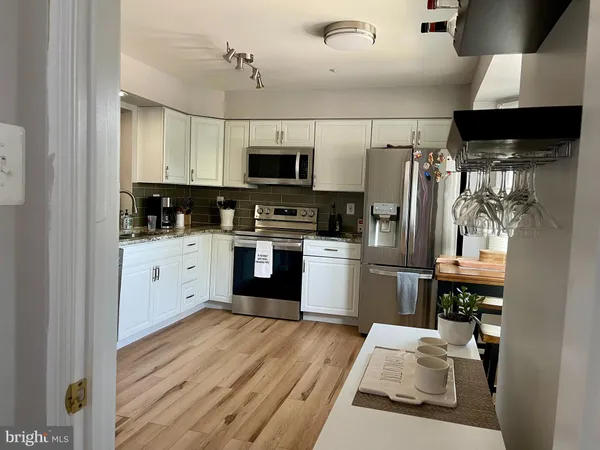 a kitchen with stainless steel appliances kitchen island granite countertop a refrigerator a stove top oven a sink and dishwasher