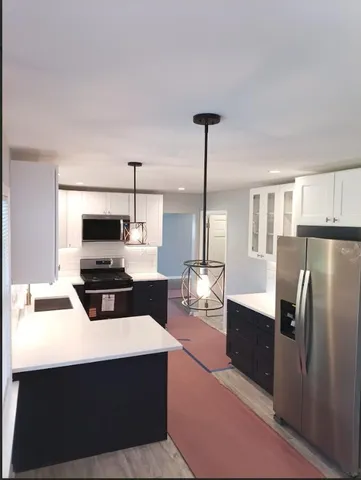 a kitchen with stainless steel appliances a stove a refrigerator a sink a oven a dining table and chairs