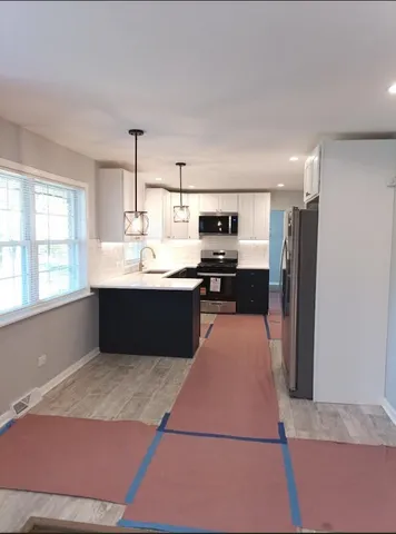 a kitchen with stainless steel appliances kitchen island sink refrigerator and window