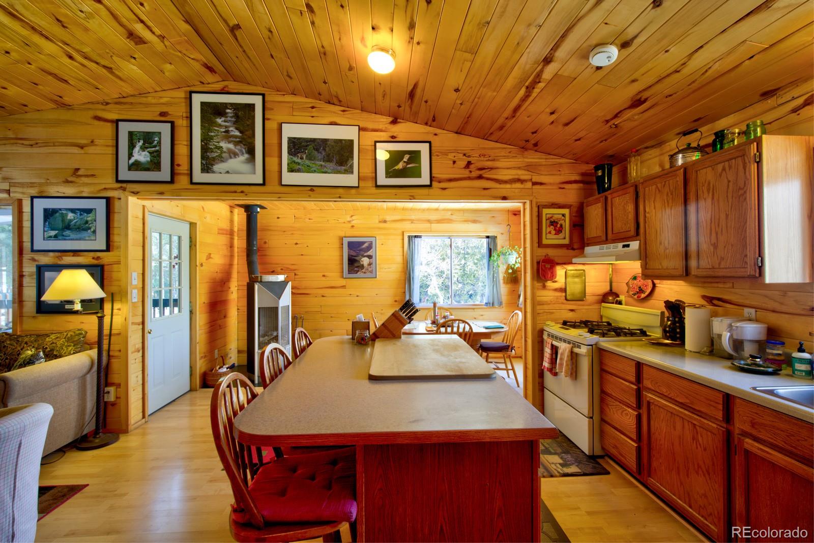 203 Hampton Run Road Mosca, CO 81146 - Photo 14 of 33 a kitchen with stainless steel appliances granite countertop a stove a refrigerator a sink a dining table and chairs with wooden floor