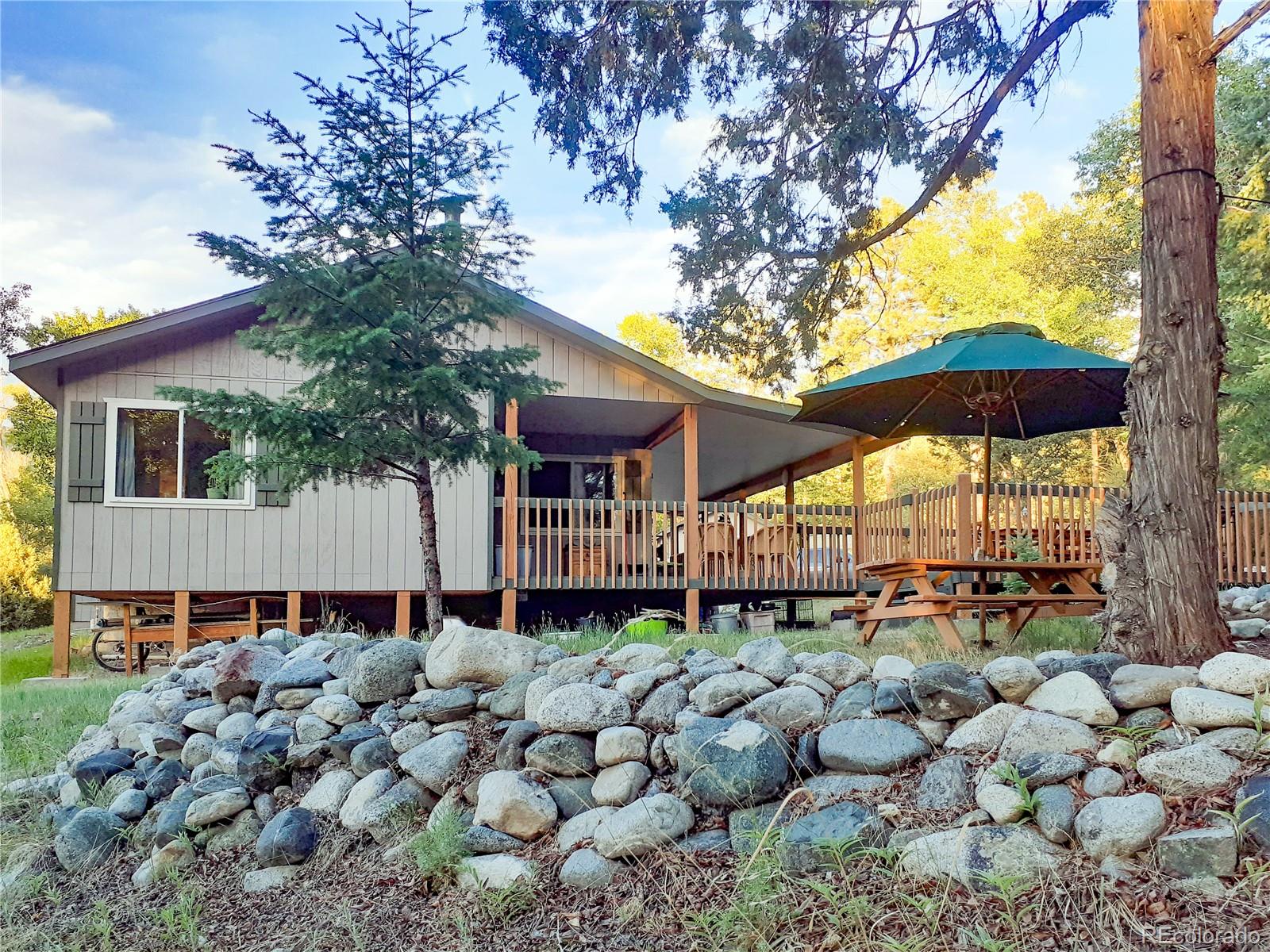 203 Hampton Run Road Mosca, CO 81146 - Photo 7 of 33 a backyard of a house with barbeque oven table and chairs under an umbrella