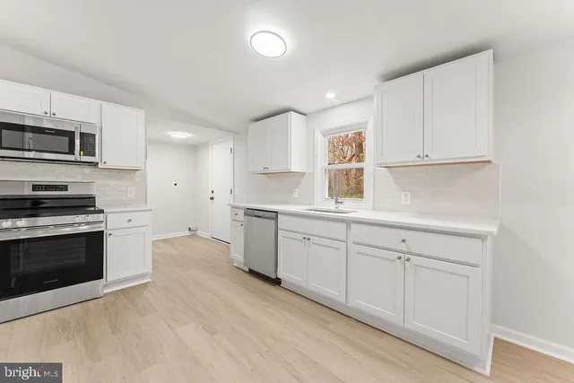 a kitchen with granite countertop white cabinets and stainless steel appliances