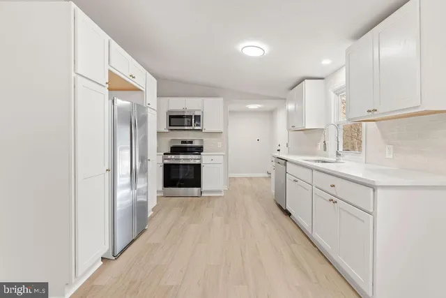a large kitchen with cabinets wooden floor and stainless steel appliances