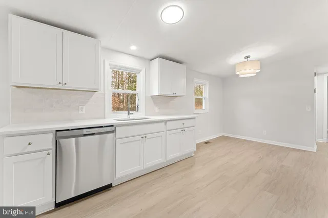 a kitchen with granite countertop white cabinets white appliances a sink and a window