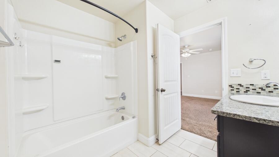 3707 Rochester Avenue Lubbock, TX 79407 - Photo 24 of 40 a bathroom with a granite countertop sink a mirror a bathtub and shower