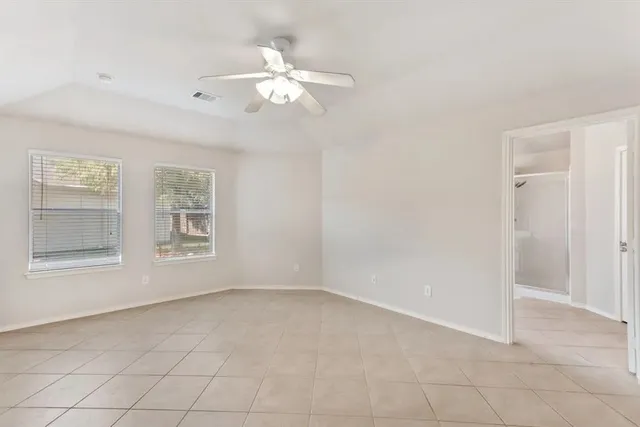 an empty room with windows and fan