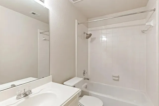 a bathroom with a bathtub shower sink vanity and toilet