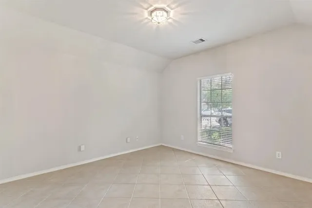 an empty room with a chandelier fan and windows
