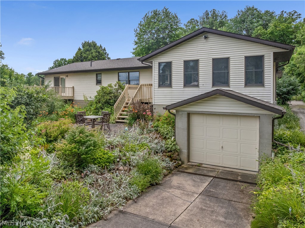 1835 Lynn Road Kent, OH 44240 - Photo 2 of 48 Exterior featuring horizontal vinyl siding, a two-story layout with an attached garage, a spacious wooden deck with stairs, a ground-level patio, and extensive landscaping