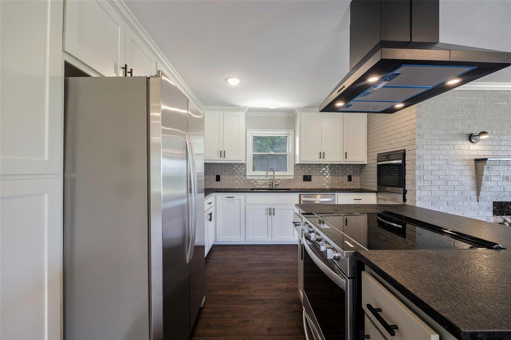 2323 Sutter Street Dallas, TX 75216 - Photo 10 of 30 Kitchen featuring backsplash, island range hood, ornamental molding, dark wood-type flooring, and appliances with stainless steel finishes