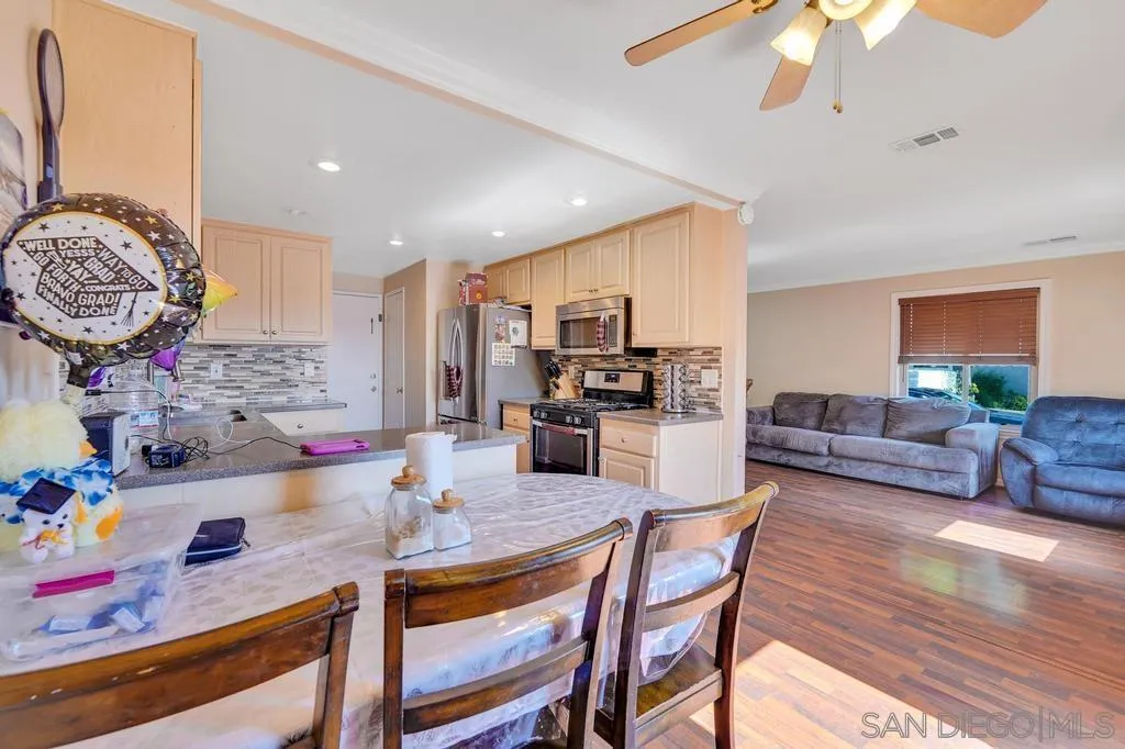 320 Grapevine Road, Unit 12 Vista, CA 92083 - Photo 11 of 50 a kitchen with stainless steel appliances granite countertop a stove a refrigerator a dining table and chairs with wooden floor