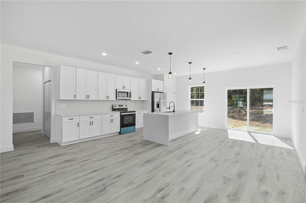 2640 West Fairway Loop Citrus Springs, FL 34434 - Photo 12 of 39 a large white kitchen with kitchen island a sink a center island stainless steel appliances and a cabinets