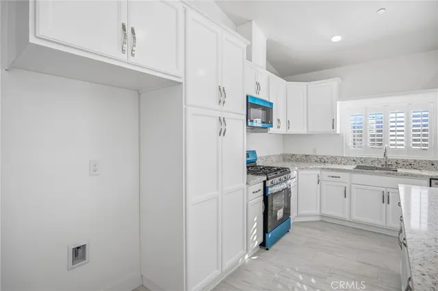 a kitchen with stainless steel appliances granite countertop white cabinets and a stove top oven