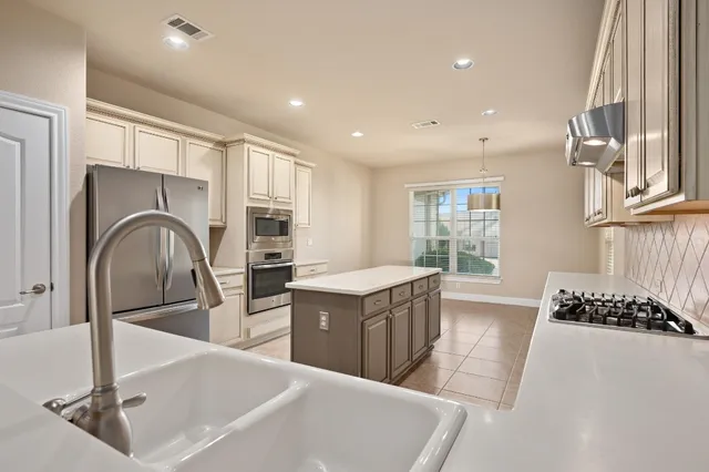 a kitchen with stainless steel appliances granite countertop a sink and a refrigerator
