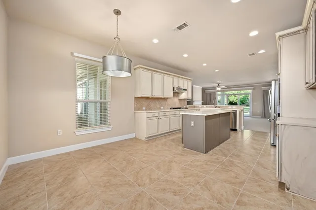 a open kitchen with a refrigerator a sink dishwasher a oven and a dining table with wooden floor