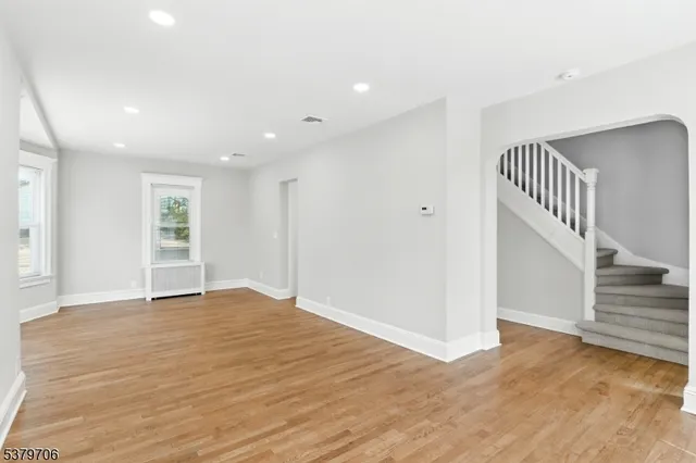 a view of an empty room with wooden floor and staircase
