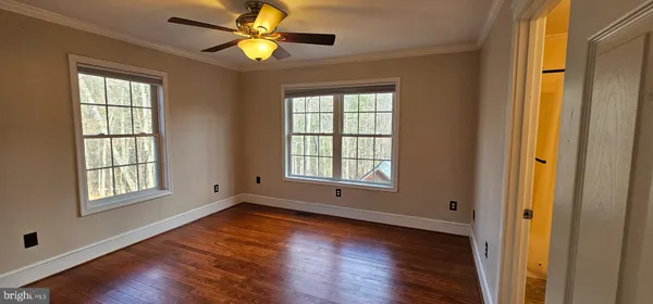 a view of an empty room with window and wooden floor