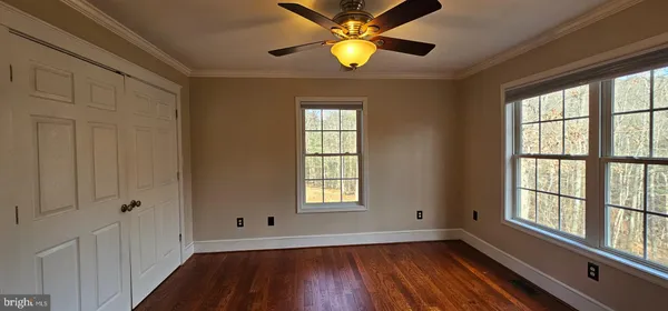 a view of an empty room with a window and wooden floor