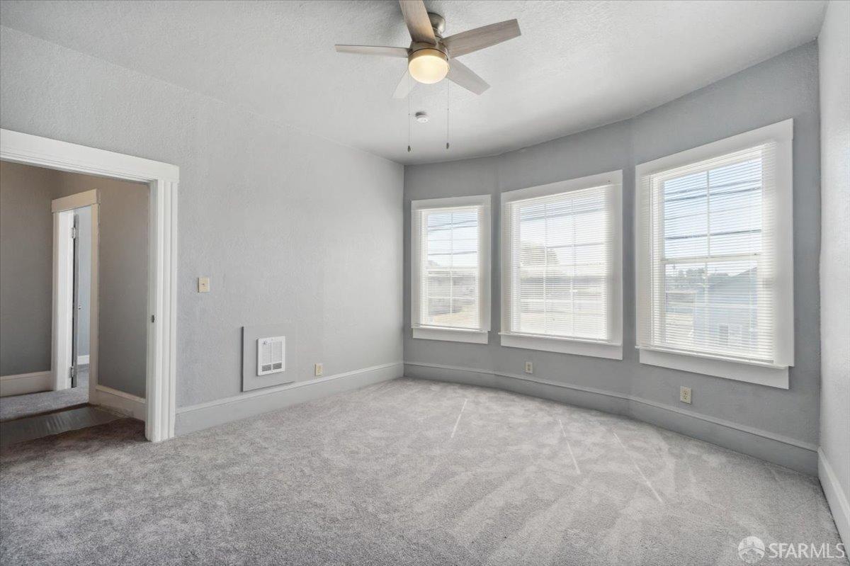 1309 80th Avenue Oakland, CA 94621 - Photo 11 of 75 an empty room with chandelier fan and windows