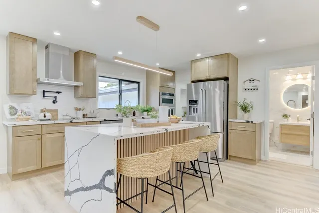 a kitchen with kitchen island a refrigerator a stove a sink and white cabinets with wooden floor