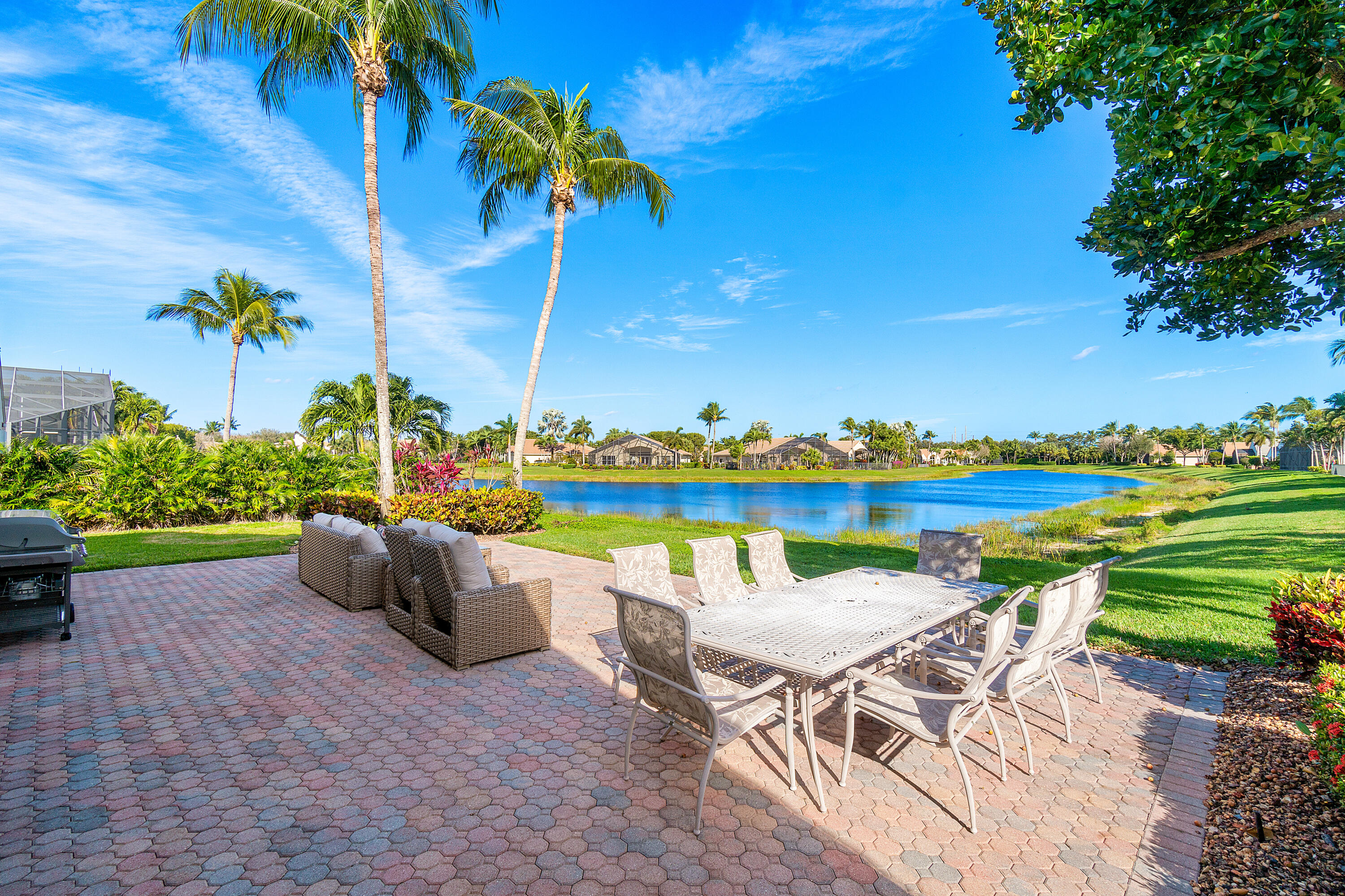 13506 Shell Beach Court Delray Beach, FL 33446 - Photo 40 of 66 a view of a lake with couches and table and chairs under an umbrella