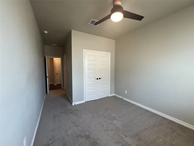 an empty room with closet and a chandelier fan