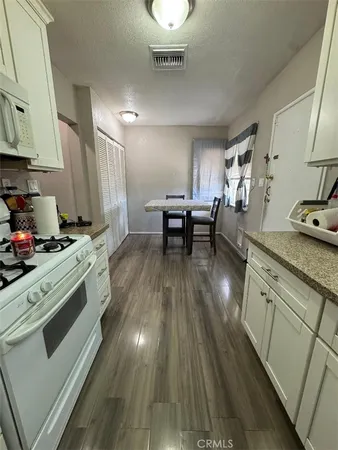 a kitchen with granite countertop wooden floors and white stainless steel appliances
